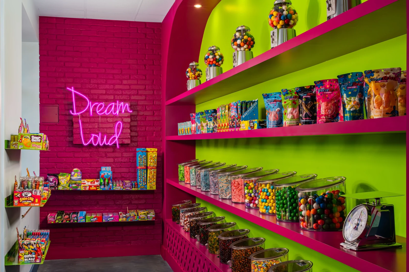 Planet’s bulk candy wall with colorful clear bins, pink brick, and green shelves
